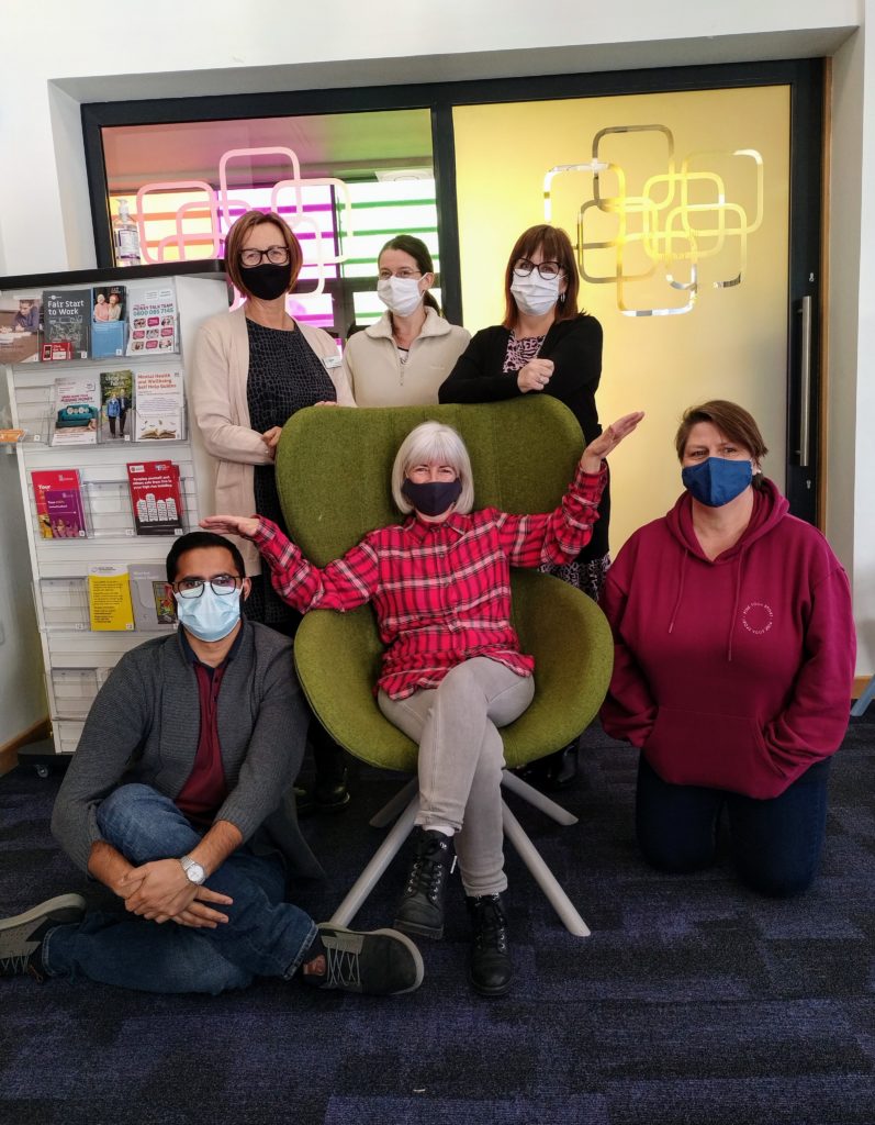A group of six senior library assistants wearing facemasks