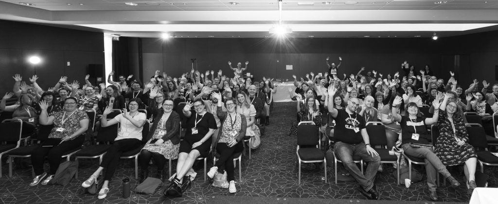 A black and white photograph of CILIPS members cheering at the 2022 CILIPS Annual Conference.