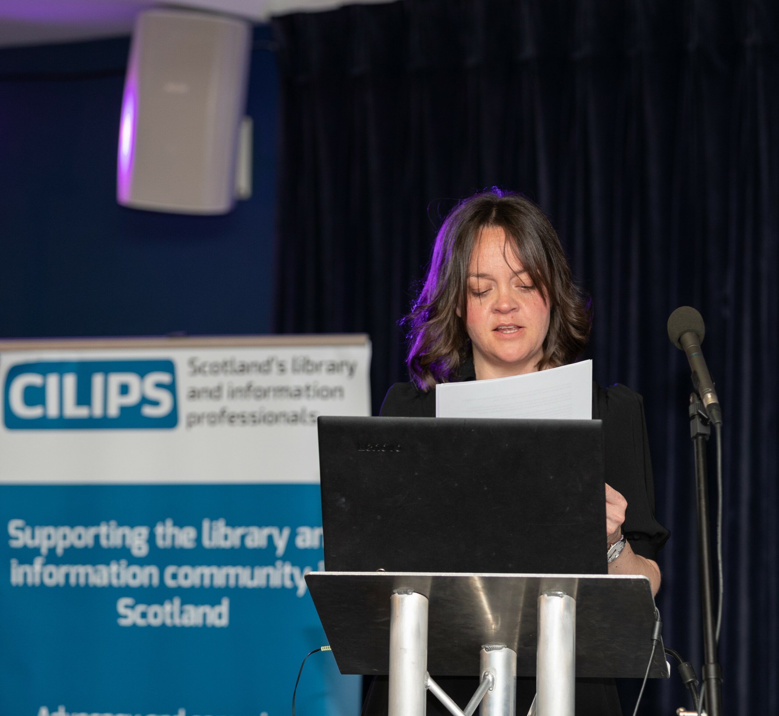 Scotland on Sunday editor and CILIPS Honorary Member Catherine Salmond addresses CILIPS22 delegates with a CILIPS banner behind her.