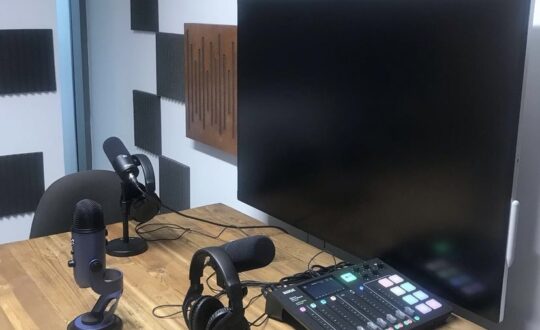 Podcast studio and equipment including mics, screen and sound deck.