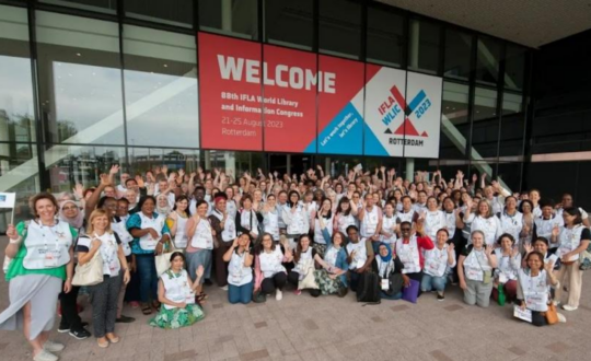 Volunteers in white tabards beneath a Welcome sign at the IFLA Congress in Rotterdam, 2023.