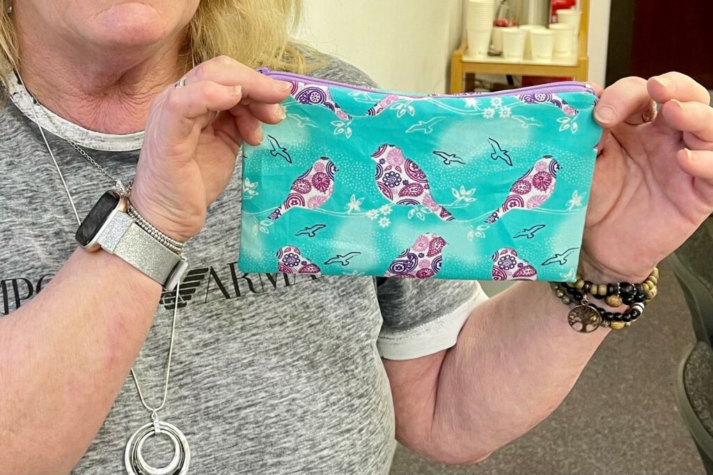 A 'Green Pages' Sewing Skills workshop attendee holding up a handcrafted pencil case.
